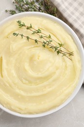 Photo of Bowl of tasty mashed potato with rosemary on grey marble table, flat lay