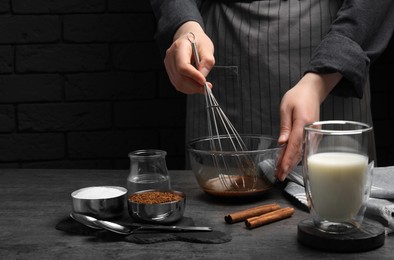 Photo of Woman whipping cream for dalgona coffee at grey table, closeup