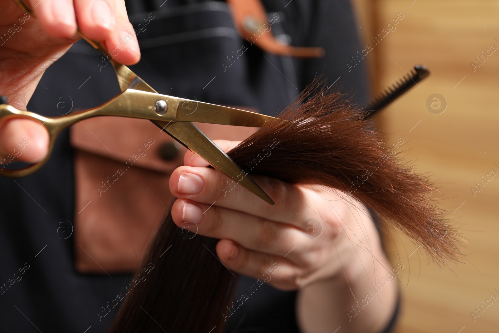 Photo of Hairdresser cutting client's hair with scissors in salon, closeup