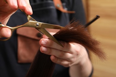 Photo of Hairdresser cutting client's hair with scissors in salon, closeup