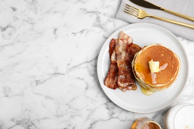 Delicious pancakes with maple syrup, butter and fried bacon on white marble table, flat lay. Space for text