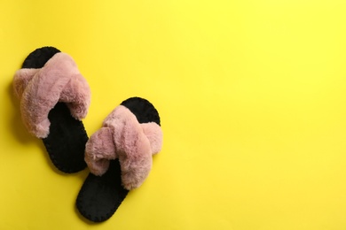 Photo of Pair of soft slippers on yellow background, flat lay. Space for text