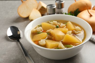 Photo of Bowl of delicious turnip soup served on light grey table