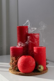 Photo of Red candles with Christmas decor on white table