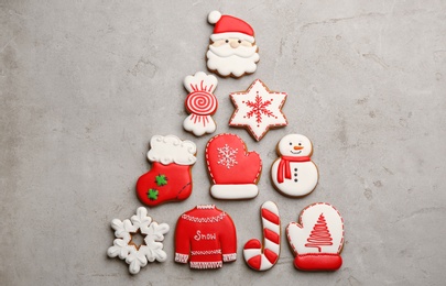 Photo of Christmas tree shape made of delicious decorated gingerbread cookies on light table, flat lay