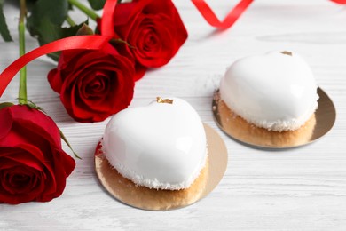 Photo of St. Valentine's Day. Delicious heart shaped cakes and roses on white wooden table, closeup