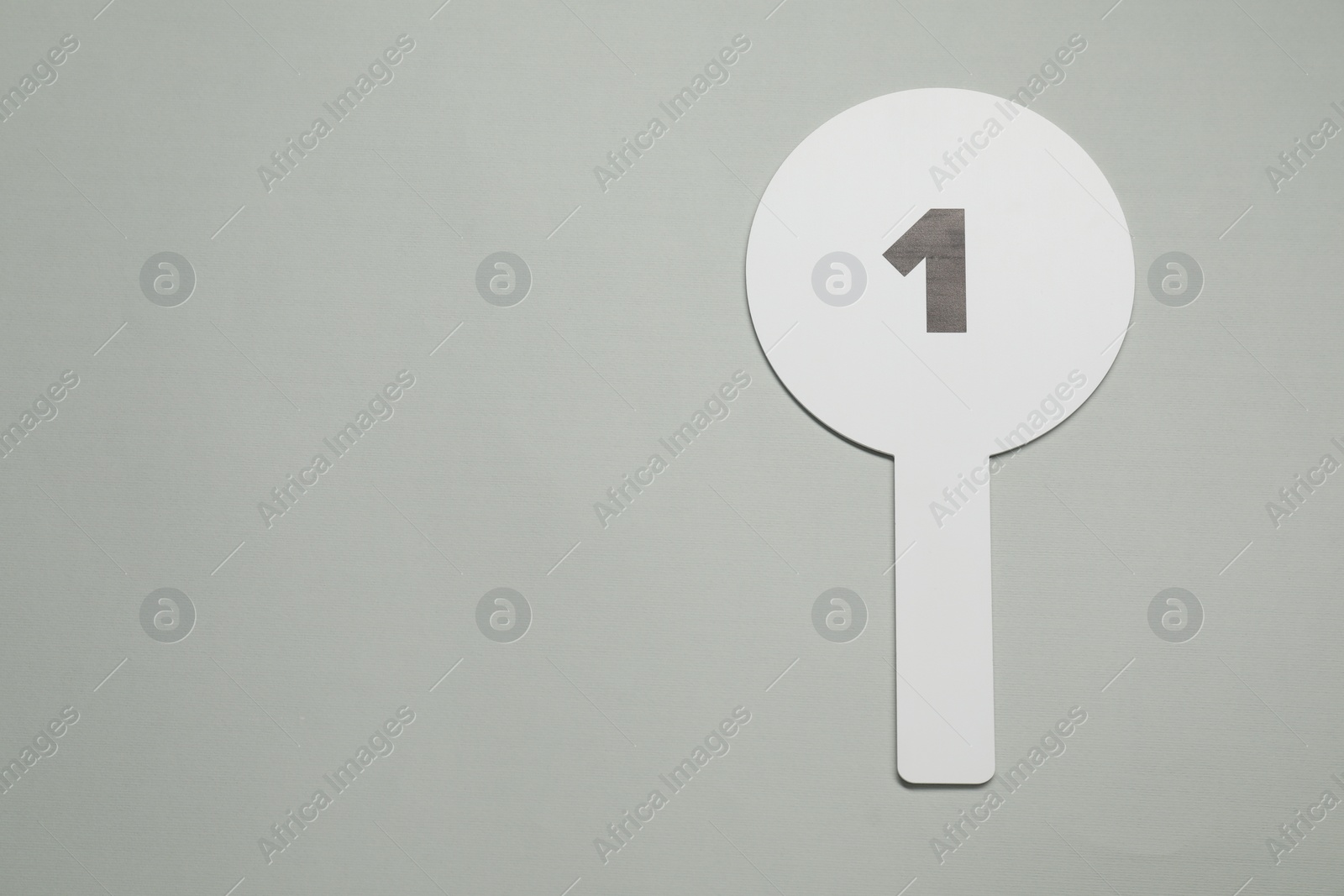 Photo of Auction paddle with number 1 on light grey background, top view. Space for text