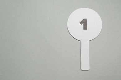 Photo of Auction paddle with number 1 on light grey background, top view. Space for text