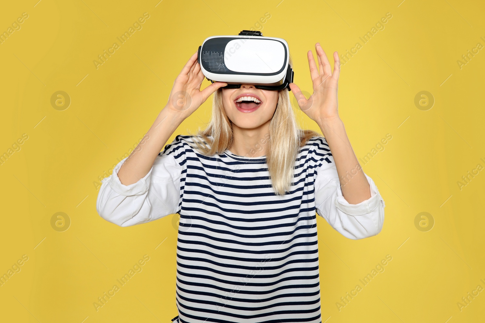 Photo of Emotional woman playing video games with virtual reality headset on color background