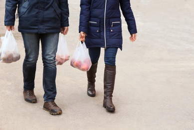 People carrying plastic bags with products outdoors, closeup