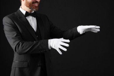 Photo of Magician in suit on black background, closeup
