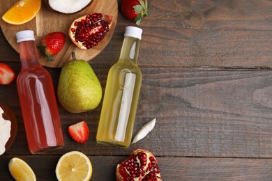 Delicious kombucha in glass bottles and fresh fruits on wooden table, flat lay. Space for text