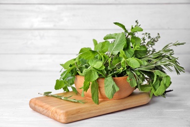 Bowl with fresh green herbs on wooden table