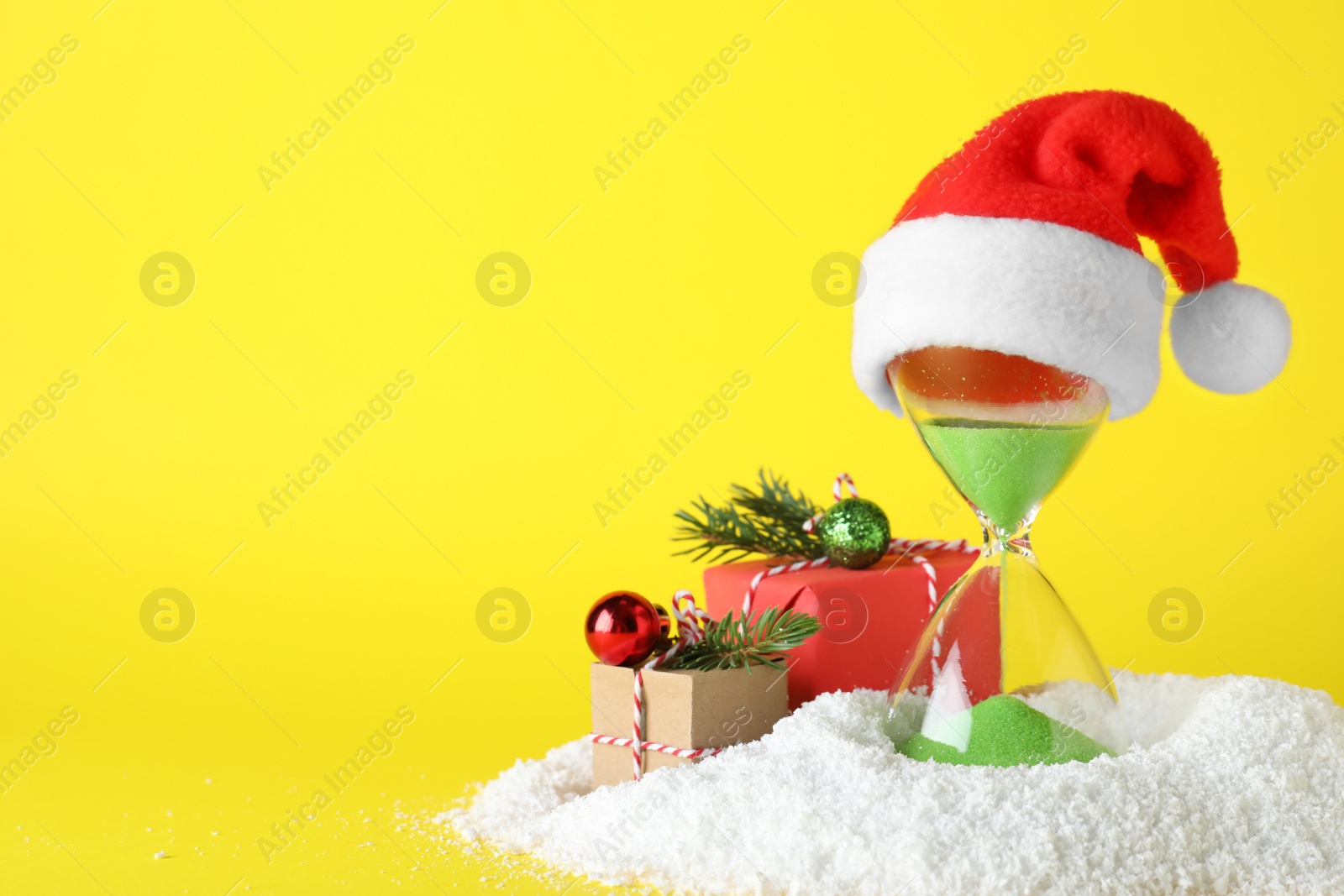 Photo of Festive composition with hourglass on yellow background, space for text. Christmas countdown