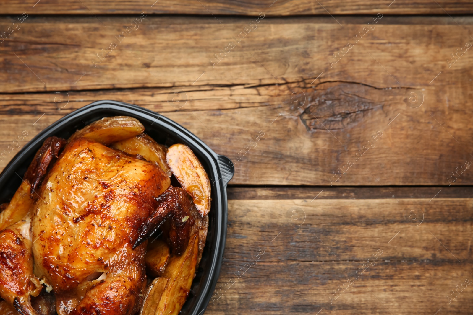 Photo of Top view of delicious grilled chicken with potato in plastic container on wooden table, space for text. Food delivery service