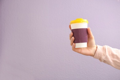 Photo of Woman holding takeaway paper coffee cup on color background. Space for text