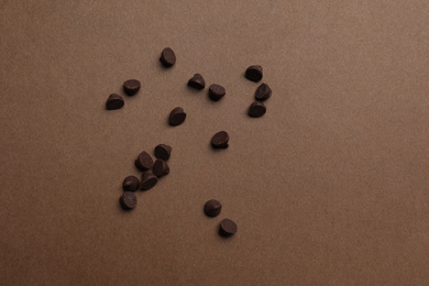 Photo of Delicious chocolate chips on brown background, top view