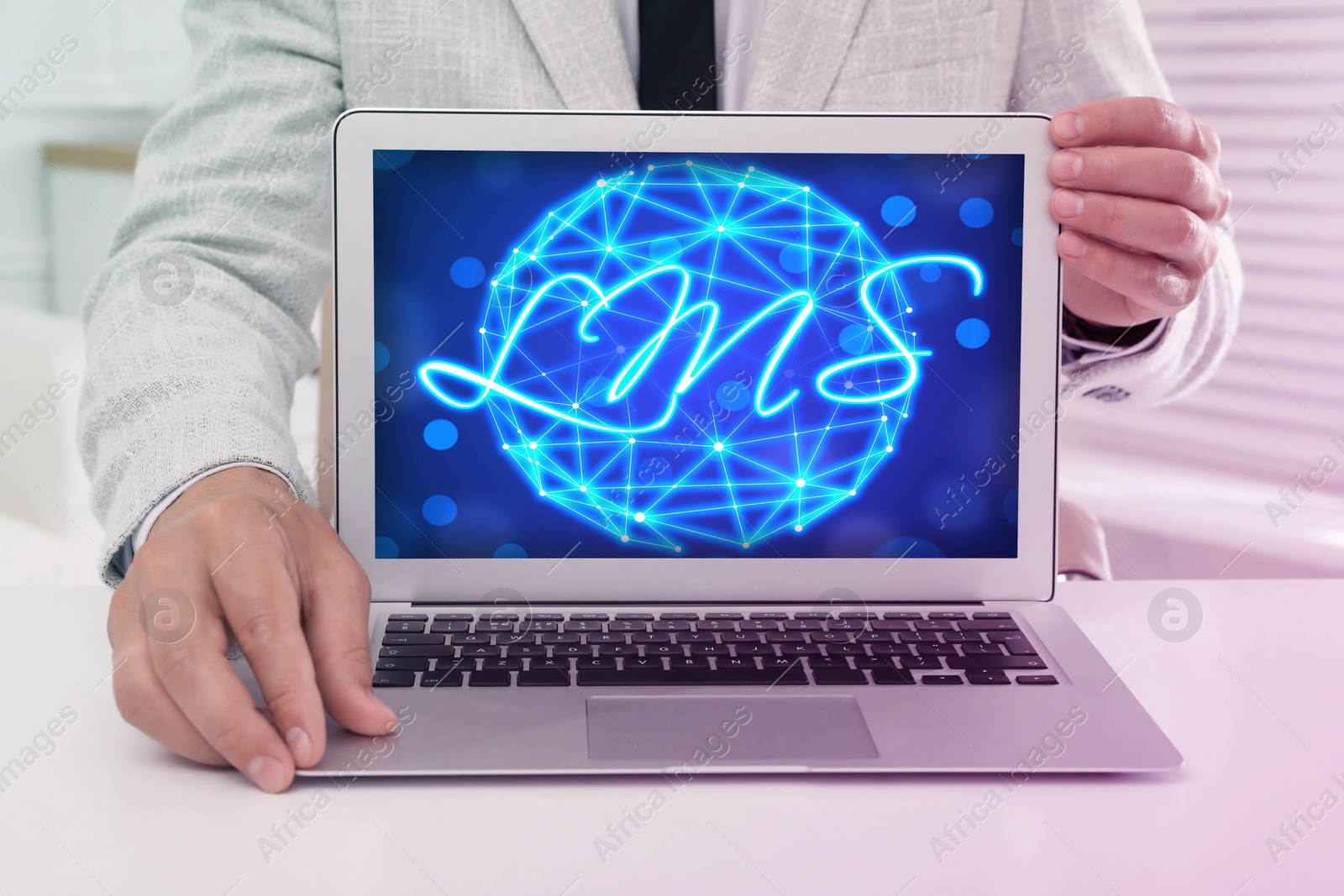 Image of Learning management system. Man showing modern laptop at table, closeup. Digital globe and abbreviation LMS on screen