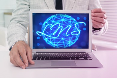 Image of Learning management system. Man showing modern laptop at table, closeup. Digital globe and abbreviation LMS on screen