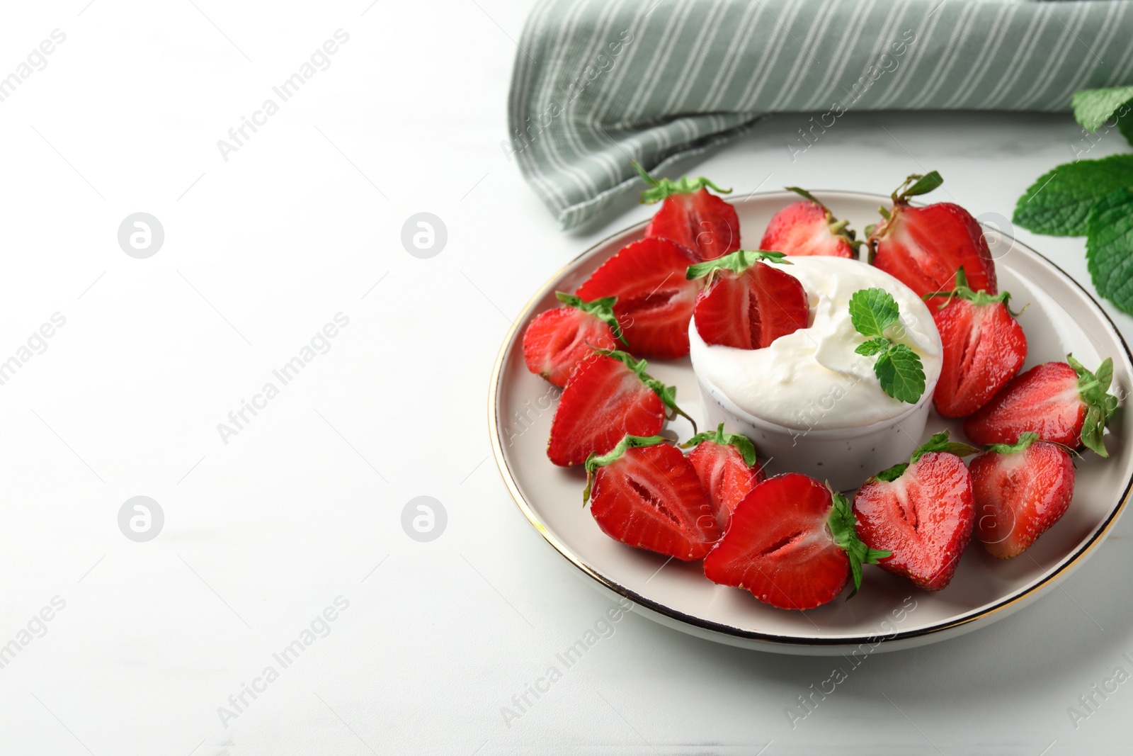 Photo of Delicious strawberries with whipped cream on white table, space for text