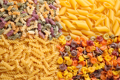 Photo of Different types of pasta as background, top view