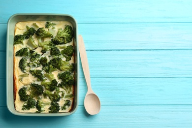 Photo of Tasty broccoli casserole in baking dish on blue wooden table, top view. Space for text