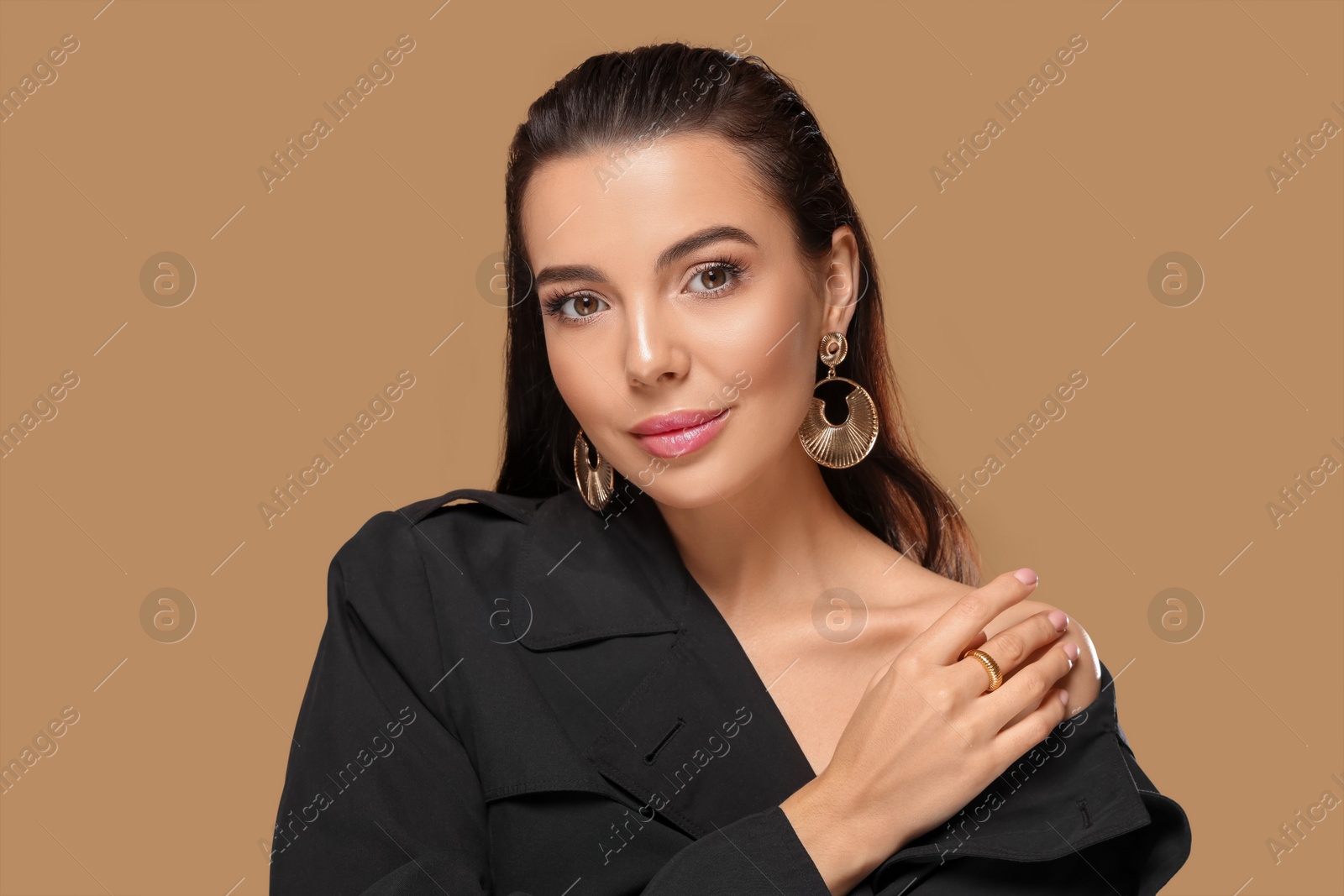 Photo of Portrait of young woman with beautiful makeup on light brown background