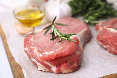 Photo of Fresh raw meat with rosemary on wooden board, closeup