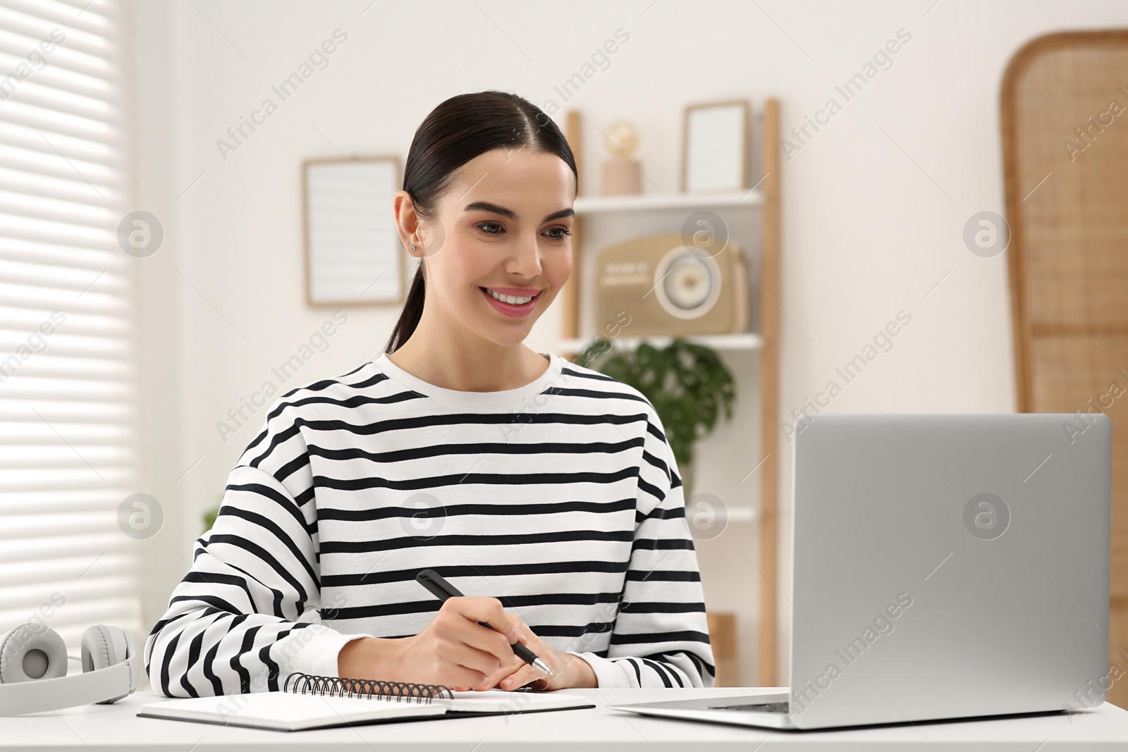 Photo of Online translation course. Student writing near laptop at home