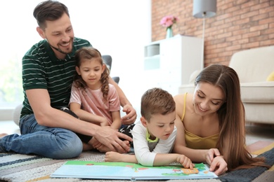 Young couple reading book with children at home. Happy family