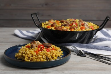 Photo of Delicious pilaf with meat, carrot and chili pepper on wooden table