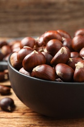 Photo of Fresh sweet edible chestnuts on wooden table, closeup