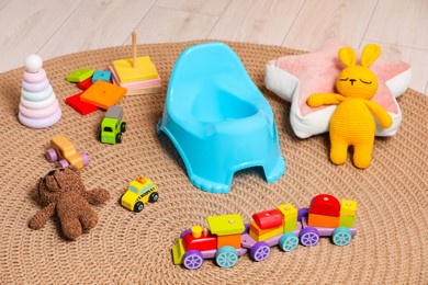 Light blue baby potty and many toys on floor. Toilet training