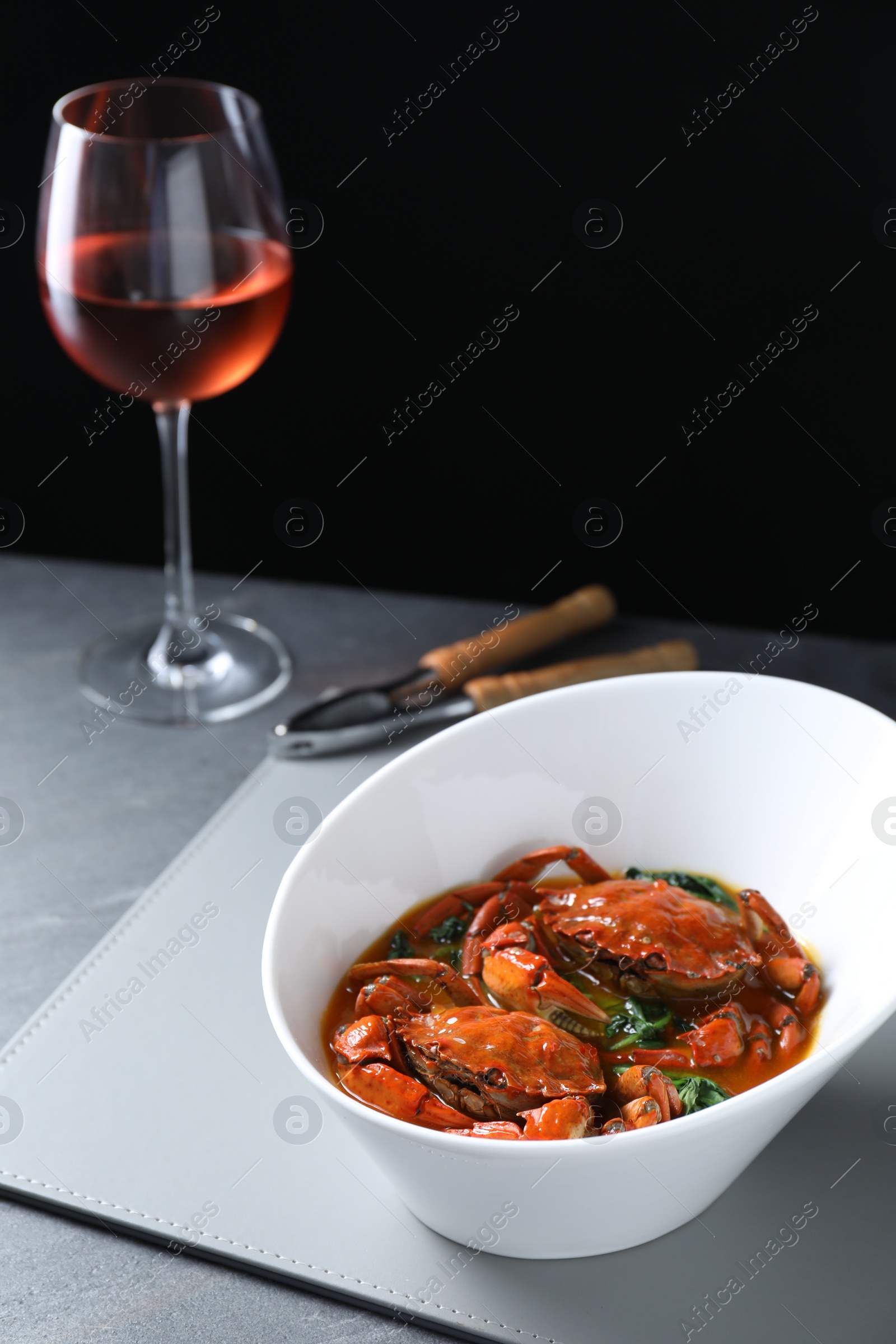 Photo of Delicious boiled crabs with sauce, glasswine and cracker on grey table, space for text