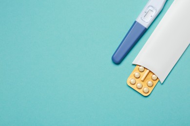 Photo of Birth control pills and pregnancy test on light blue background, top view. Space for text