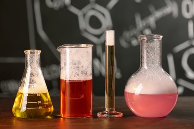 Photo of Laboratory glassware with colorful liquids on black table. Chemical reaction