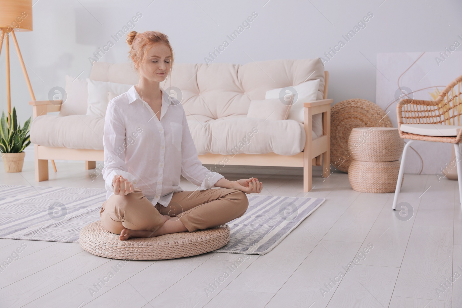 Photo of Woman meditating on wicker mat at home. Space for text