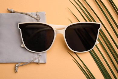 Photo of Stylish sunglasses with bag on beige background, top view