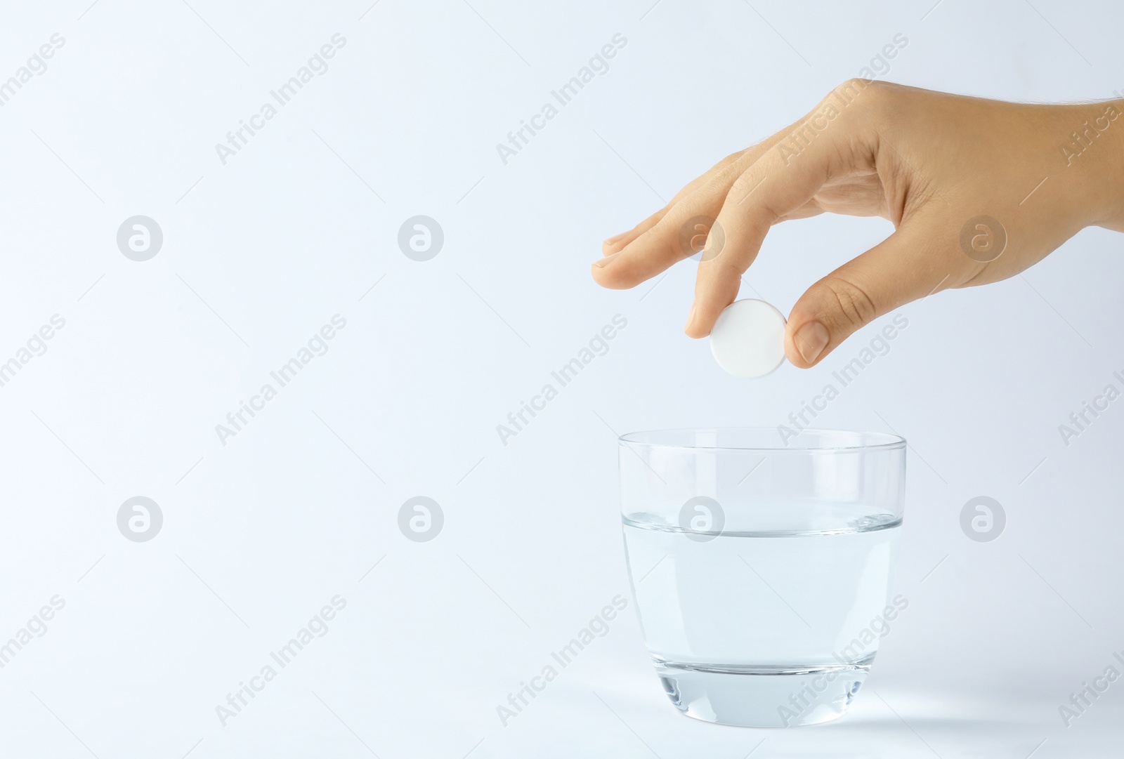 Photo of Woman putting tablet into glass of water on white background, space for text