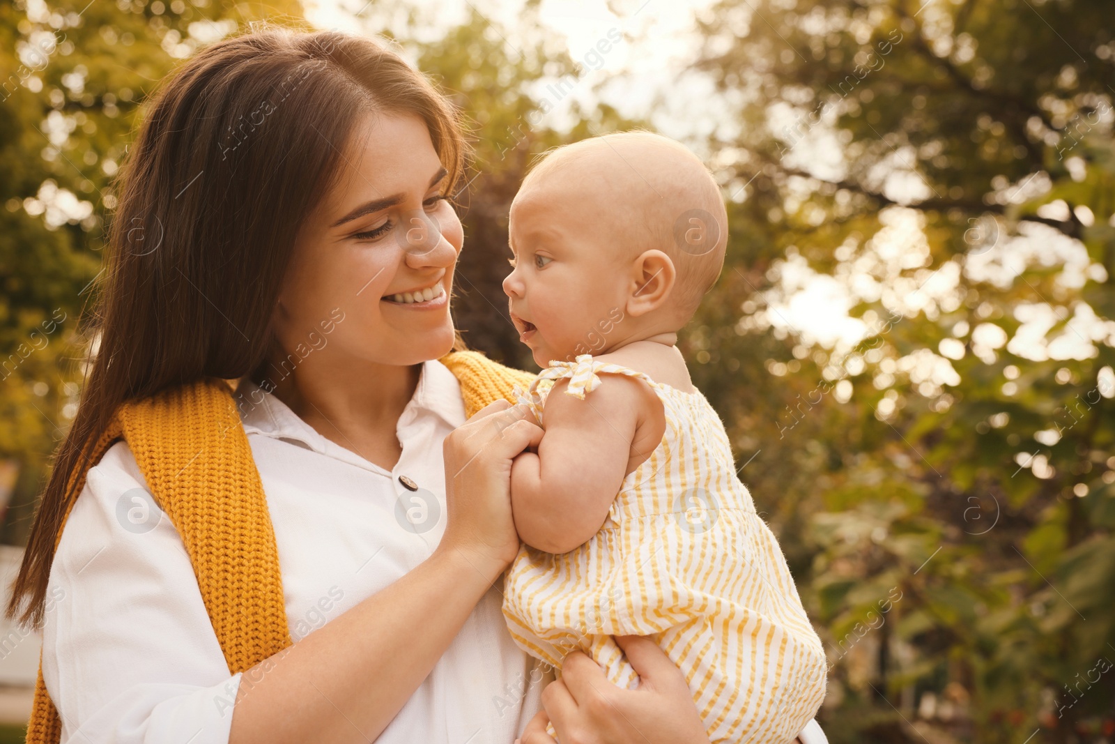 Photo of Happy mother with adorable baby walking on sunny day