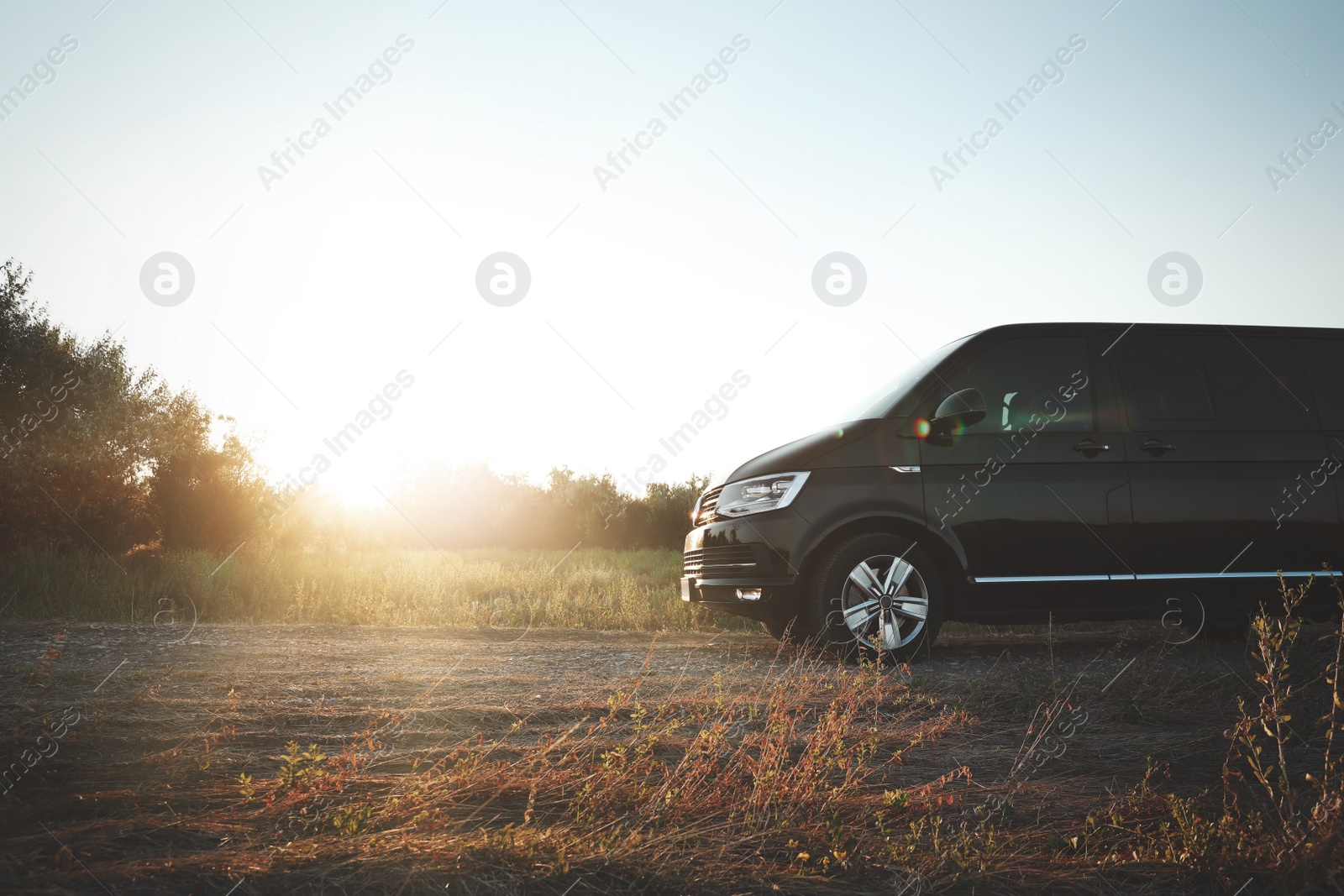 Photo of Black car on road in field at sunrise. Morning landscape