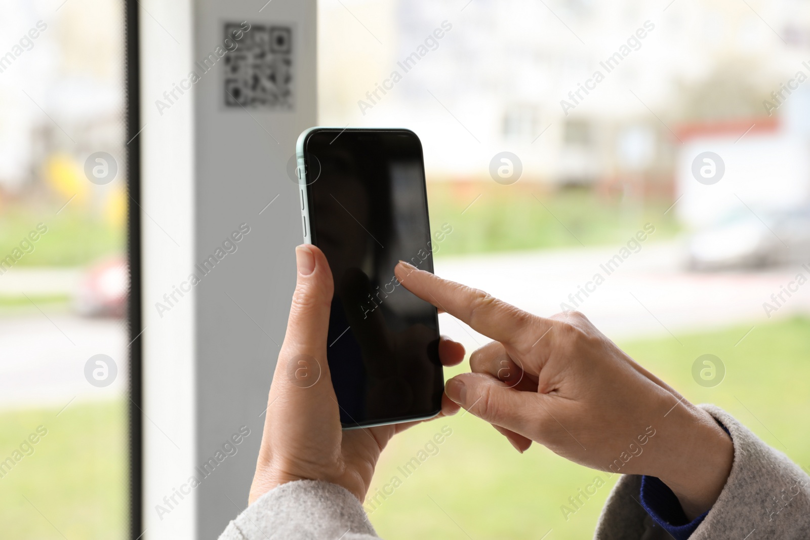 Photo of Woman scanning QR code with her smartphone in public transport, closeup