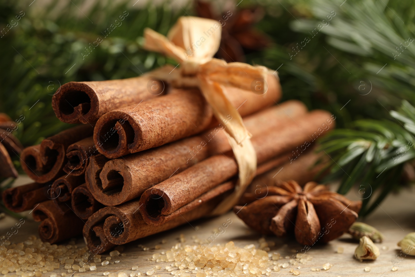 Photo of Different aromatic spices and fir branches on wooden table, closeup