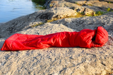 Photo of Woman resting in sleeping bag resting near lake on sunny day