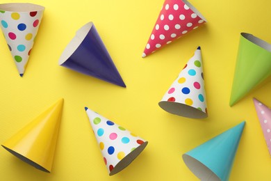 Beautiful party hats on yellow background, top view