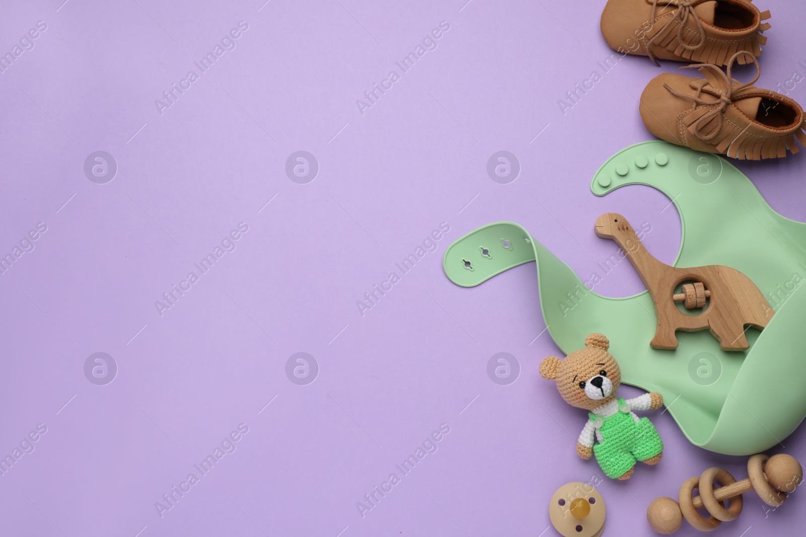 Photo of Flat lay composition with baby accessories and bib on violet background, space for text