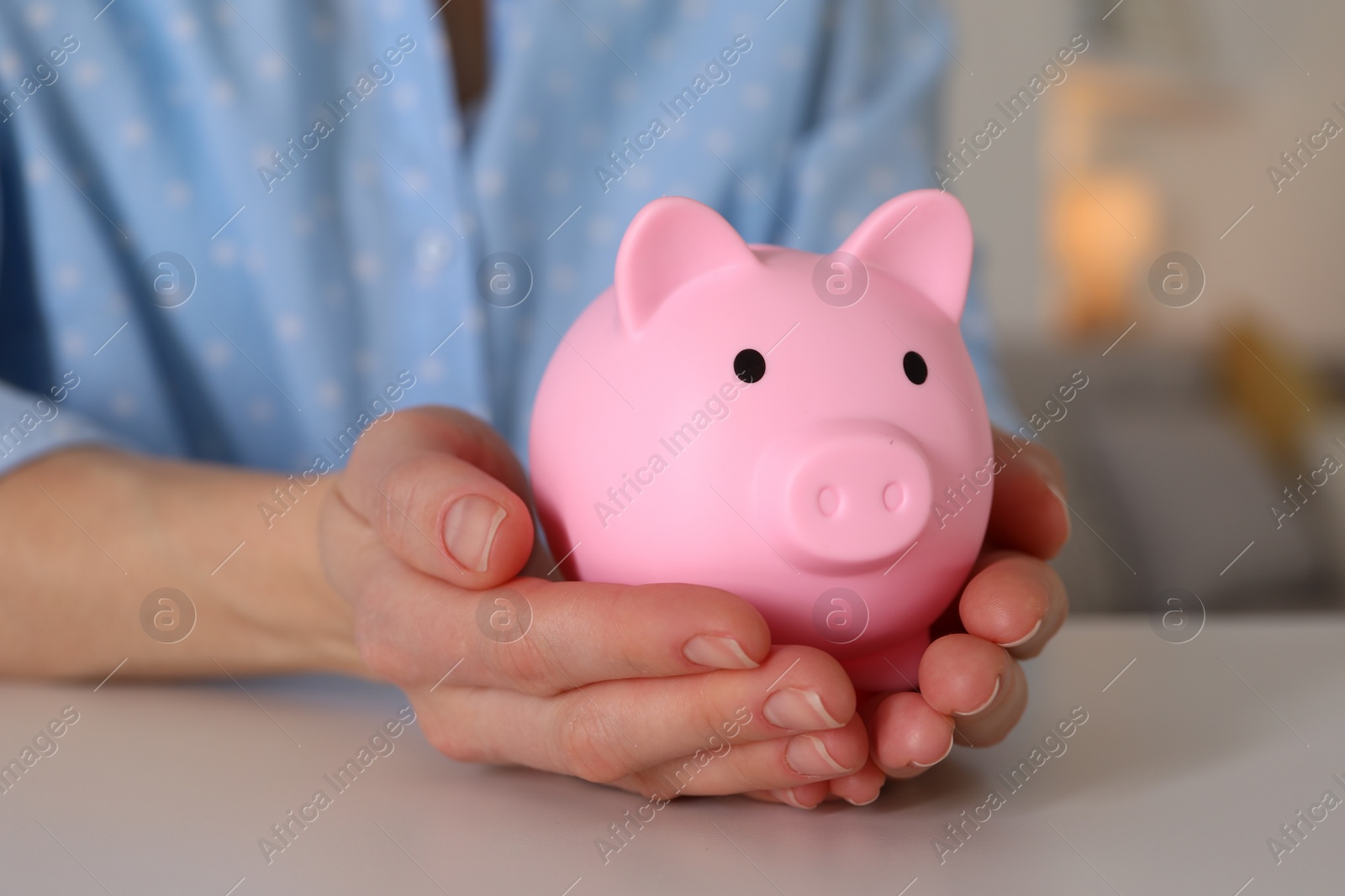 Photo of Woman with pink piggy bank at white table, closeup