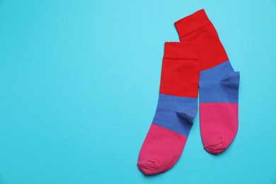 Photo of Colorful striped socks on light blue background, flat lay. Space for text