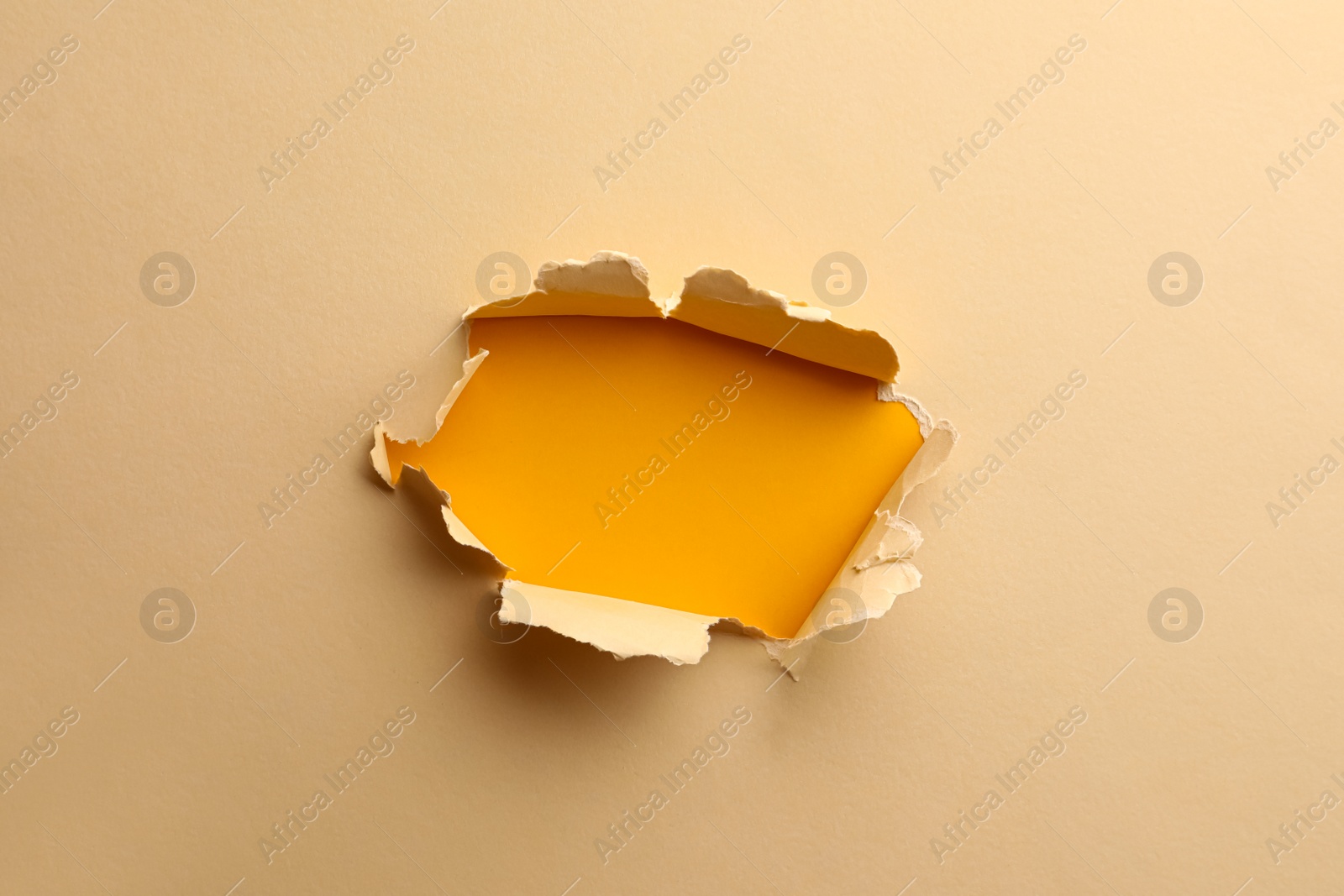 Photo of Hole in light beige paper on yellow background