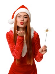 Photo of Young woman in red dress and Santa hat with burning sparkler blowing kiss on white background. Christmas celebration
